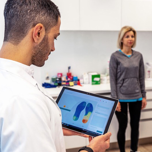 Doctor with tablet showing live biofeedback from stappone sensor soles during gait analysis with patient.