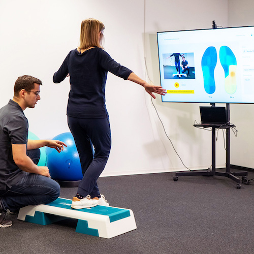 Patient does exercises using STAPPONE Physio's live biofeedback being watched by the physiotherapist