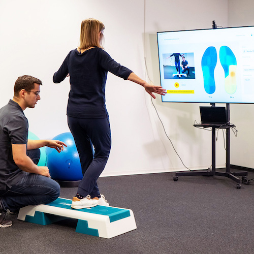 Patientin führt Übungen mit Live Biofeedback von STAPPONE Physio durch, unter Aufsicht von Physiotherapeut