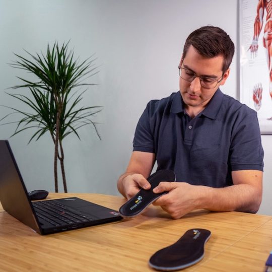 Physiotherapeut hält Sensorsohle in der Hand und betrachtete diese