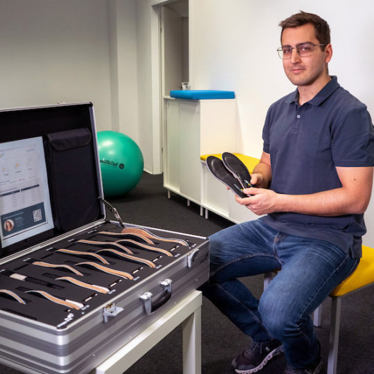 Physiotherapist next to STAPPONE Physio suitcase with sensor insoles