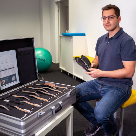 Stappone Physio Produktpaket Physiotherapeut neben STAPPONE Physio Produktkoffer mit Sensorsohlen